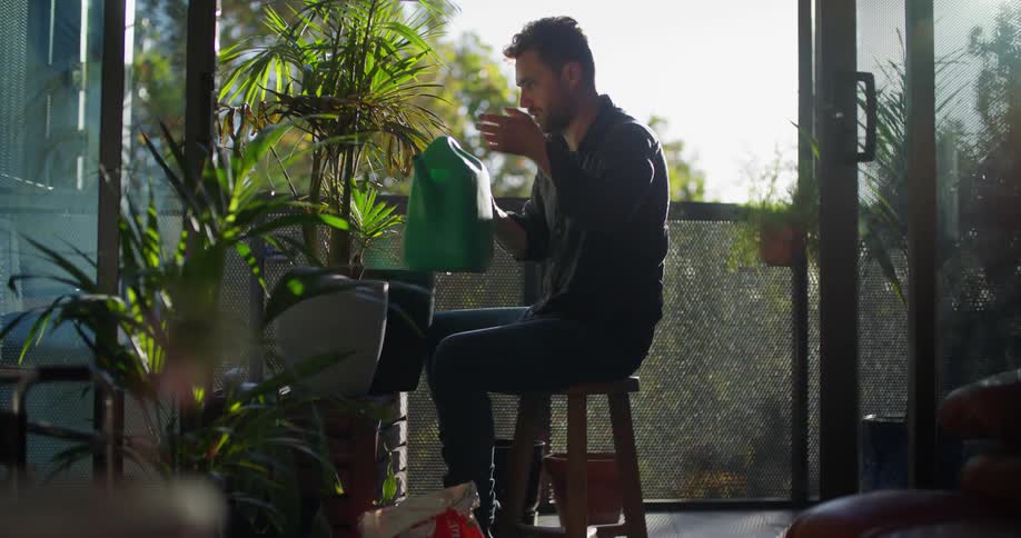 A man waters his plants on the porch