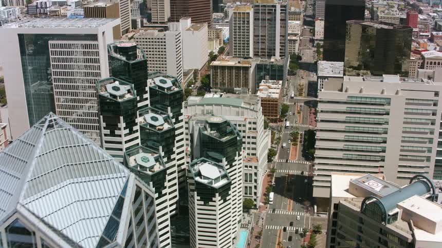 Traffic travels along a large road lined with skyscrapers in a metropolis during the day