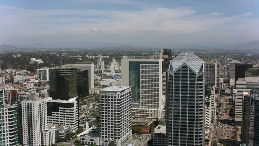 Aerial view moving over a big city with tall buildings and skyscrapers under a cloudy sky