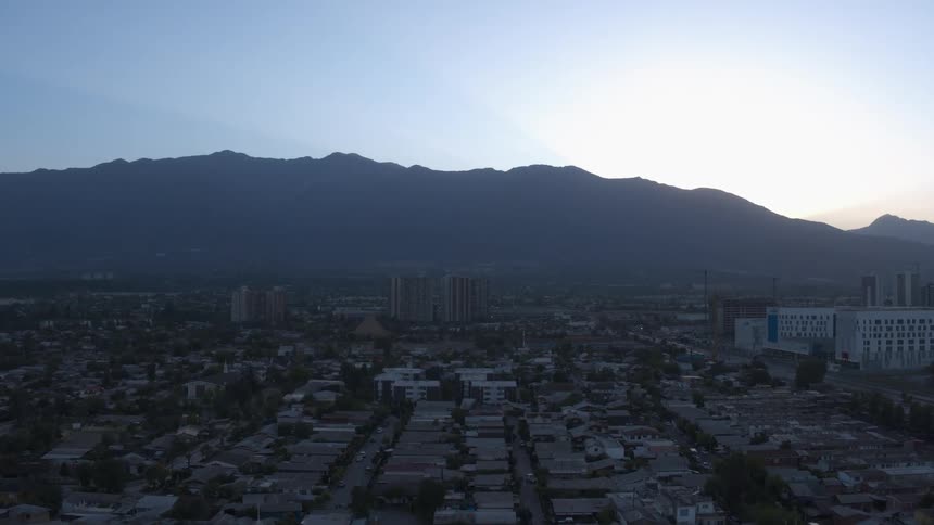 A mountain ridge looms over the buildings of a city during the day