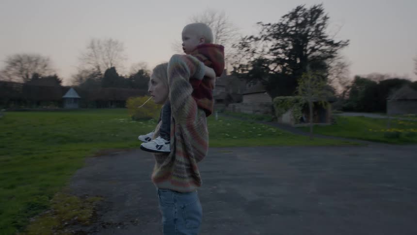 A mother gives her son a piggy back ride in the yard