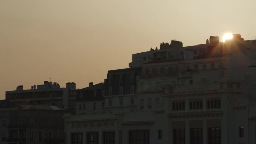The sun rises behind an apartment building