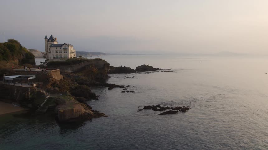 A large home sits on a cliff overlooking the ocean