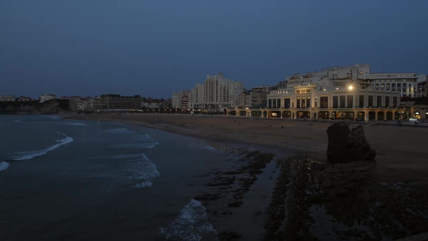 A view of a city near the ocean coast at night is displayed