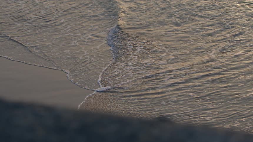 The ocean tide washes into a sandy beach