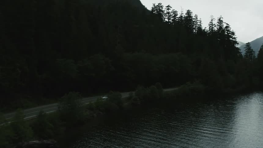 A car is driving on a rural road near a lake
