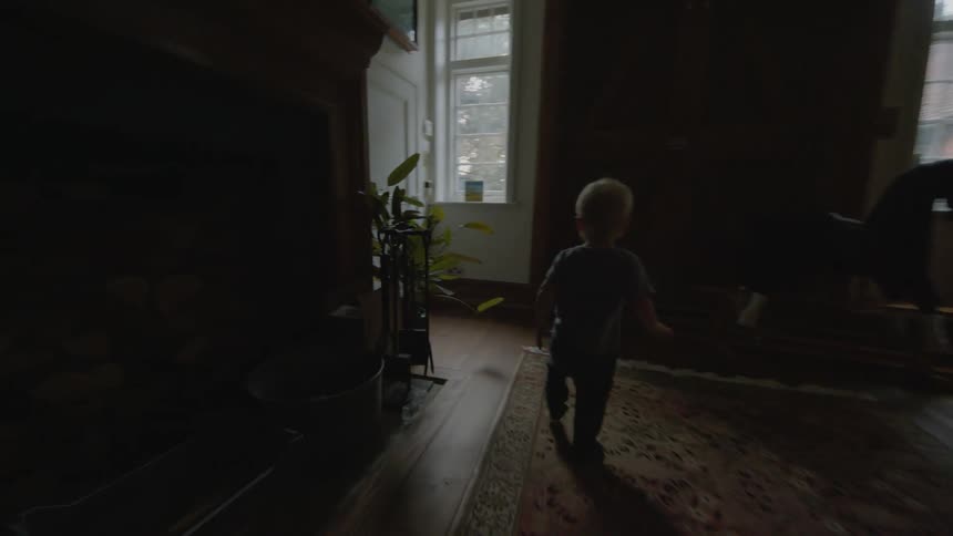 Toddler walking through the dimly lit living room to open a door at home