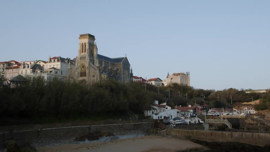 Cathedral towers in town near the river across water from boats and a parking lot