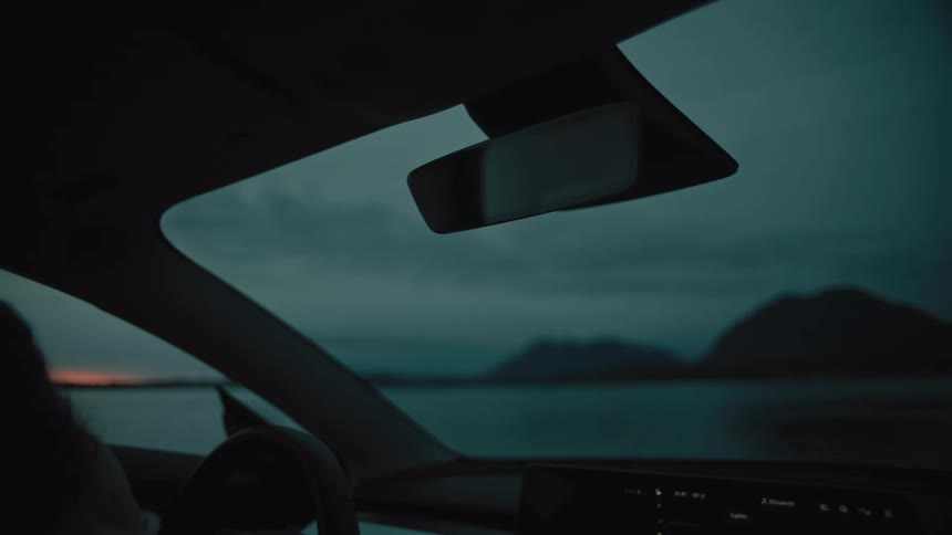 A woman parked her car along the coast and she gets out of the car and walks to the water
