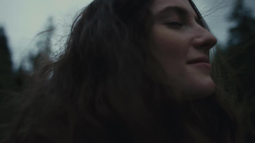 Close up of the face of a young woman smelling the aromas of a forest in the evening