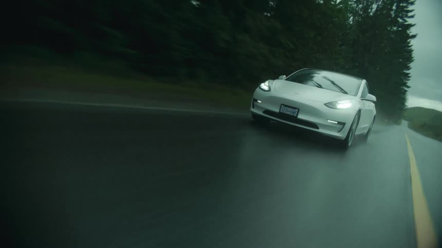 A car is speeding on the road in the rain