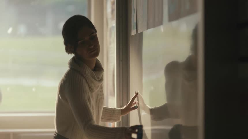 A female teacher is erasing the white board in her class room