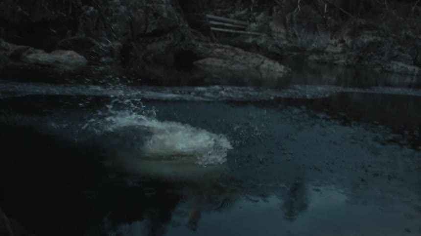 Young woman wearing a swimsuit jumps from a rock into a river