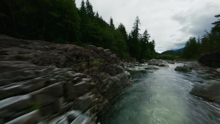 Breathtaking aerial view of a river flowing through the rocks reveals a woman standing over a promontory