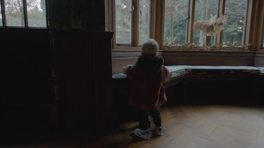 A boy is playing with a toy near the windowsill