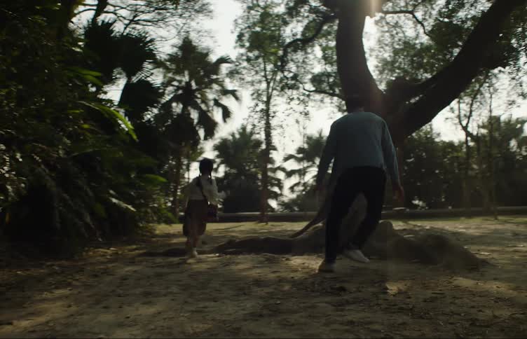 A man chases his daughter through a park