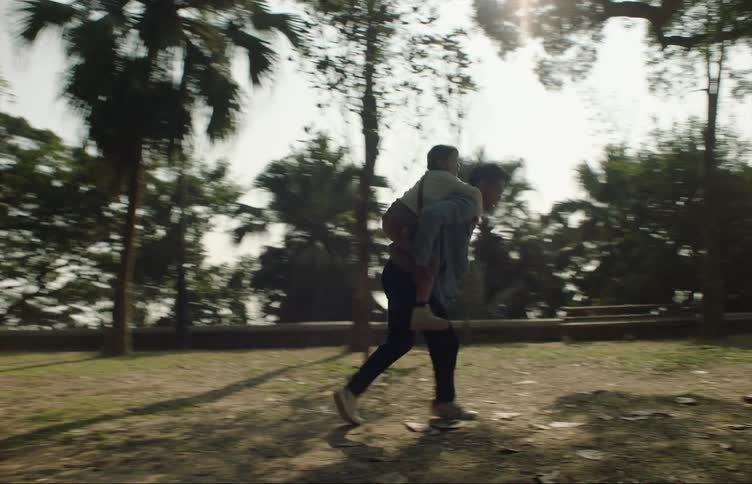 A man gives his daughter a piggyback ride through a park