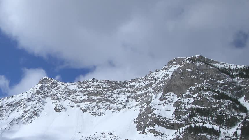 Clouds move over a snowy mountain ridge