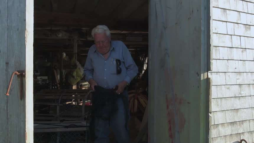 Man emerges from a lakeside shed with a fishing net in hand