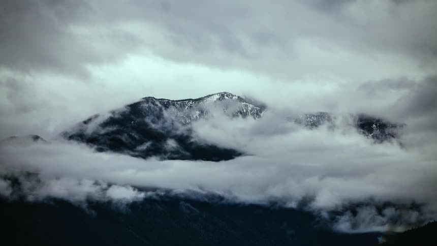 Clouds float over a snowy mountain