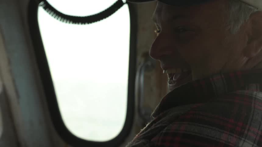 A man smiles and laughs in a boat interior