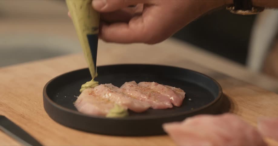 A person garnishing sliced fish
