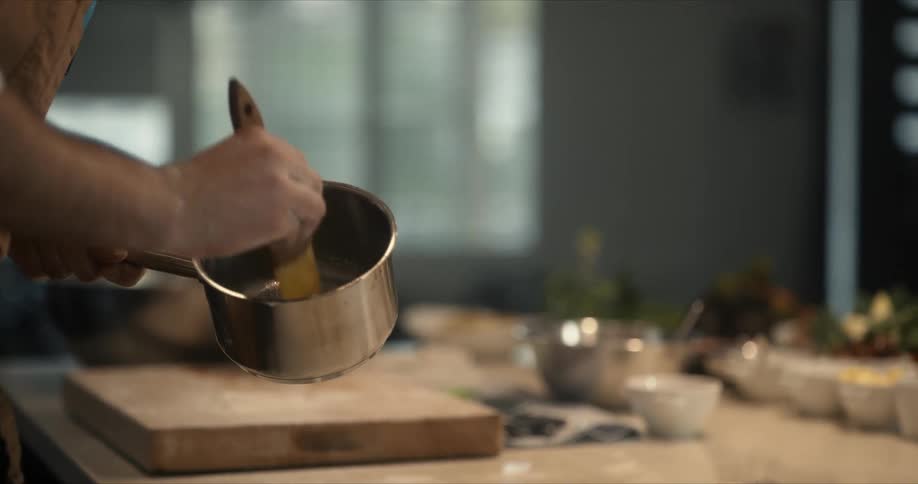 A man dips a basting brush into a pot while cooking