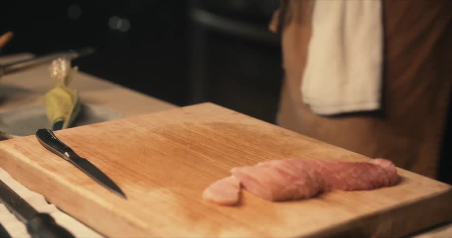 Male chef garnishes fish in dish then carries dish away