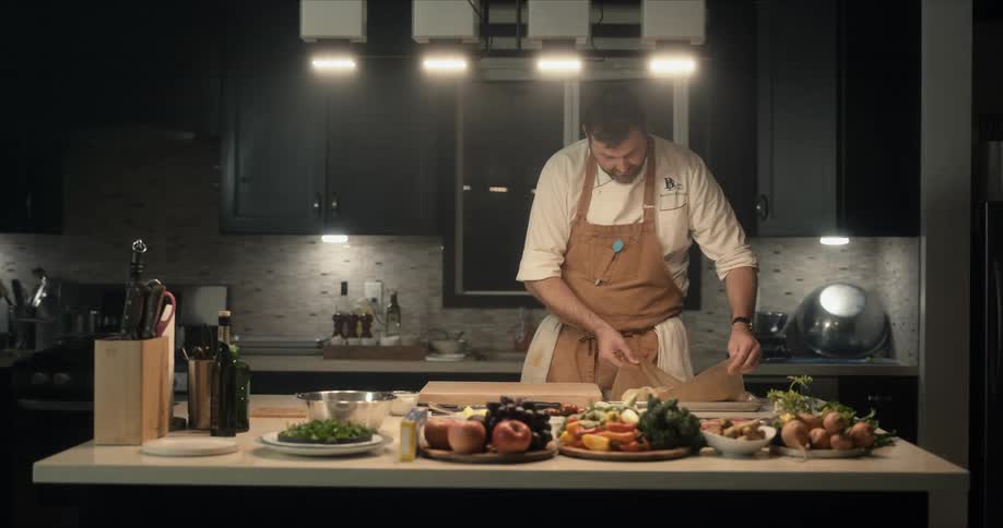 A chef lifts a baked dish on parchment and places it on the cutting board