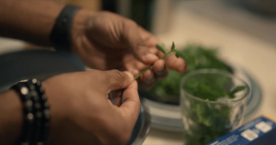 Close up of the hands of a chef cutting leafs from herbs at home
