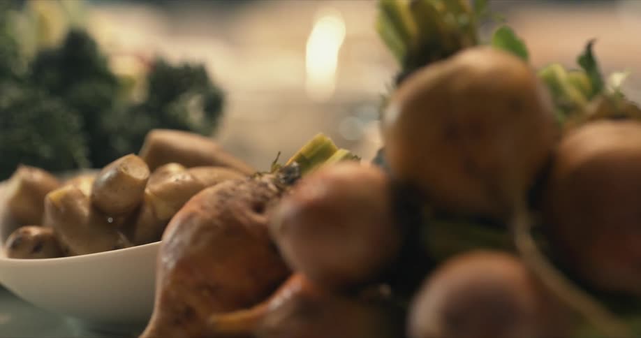 A bunch of fresh golden beets with a bowl of fingerling potatoes behind