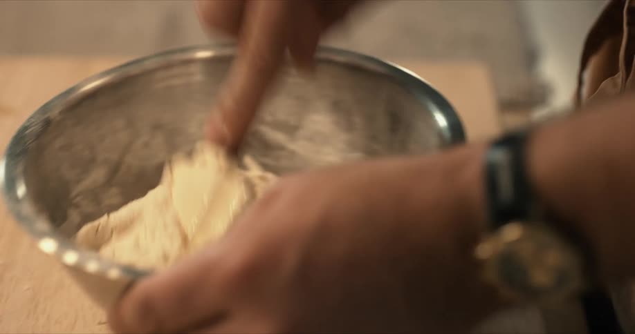 A person is mixing dough in a bowl with a spatula