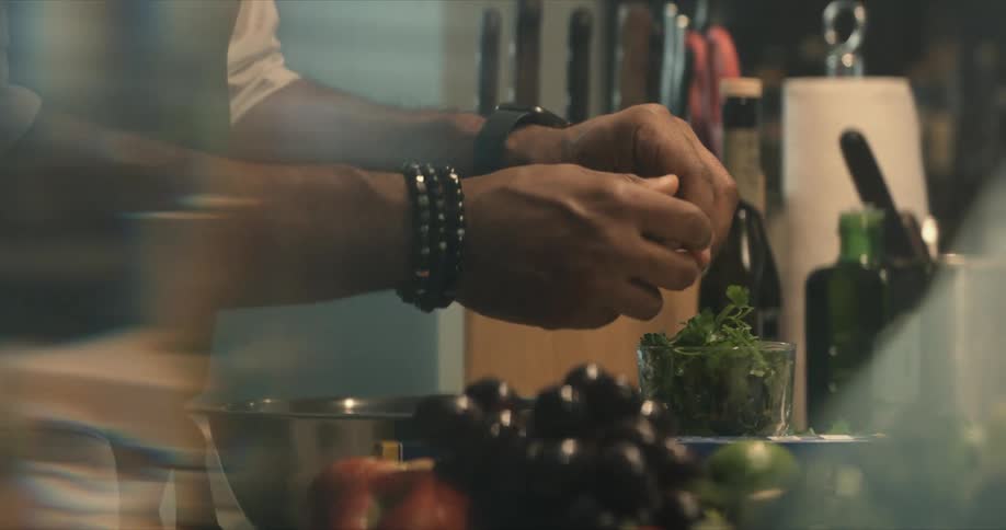 A man prepares food on a kitchen table covered in food