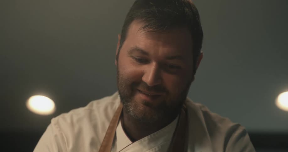 Happy chef looks up smiling while cooking at home
