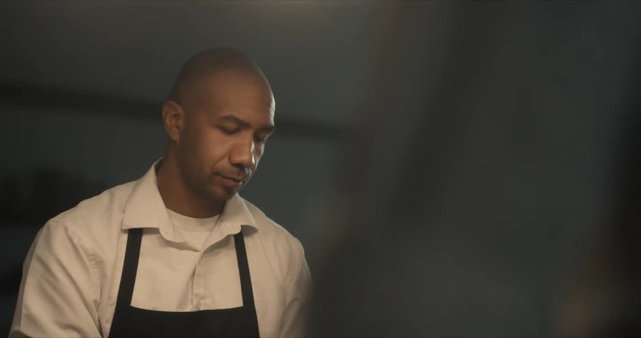 A man nods while cooking with another man in the kitchen