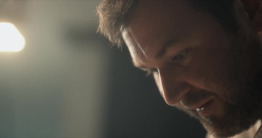 A man smiles as he looks down