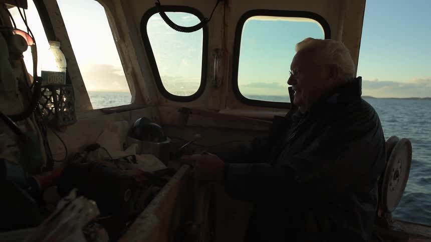 An older man is driving a boat