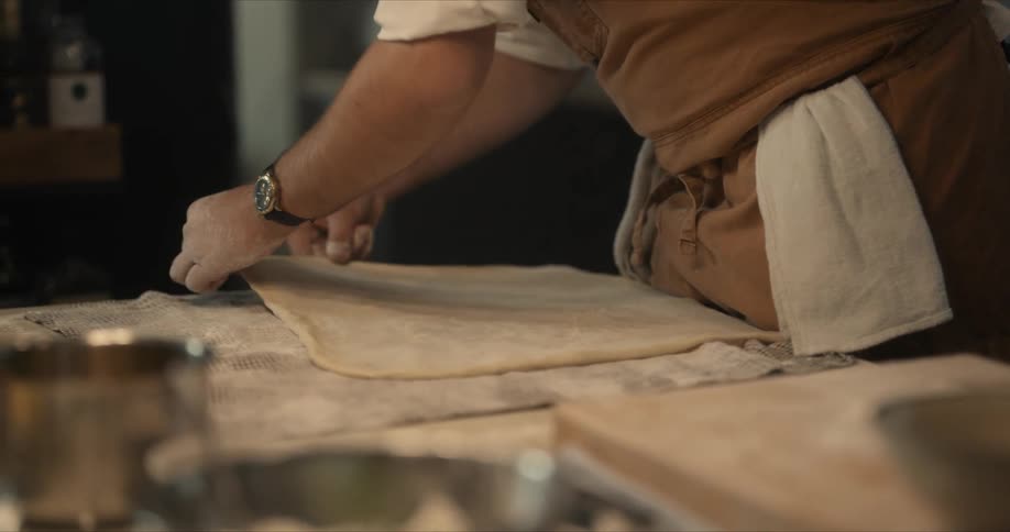 Male cook stretching dough to form a rectangle