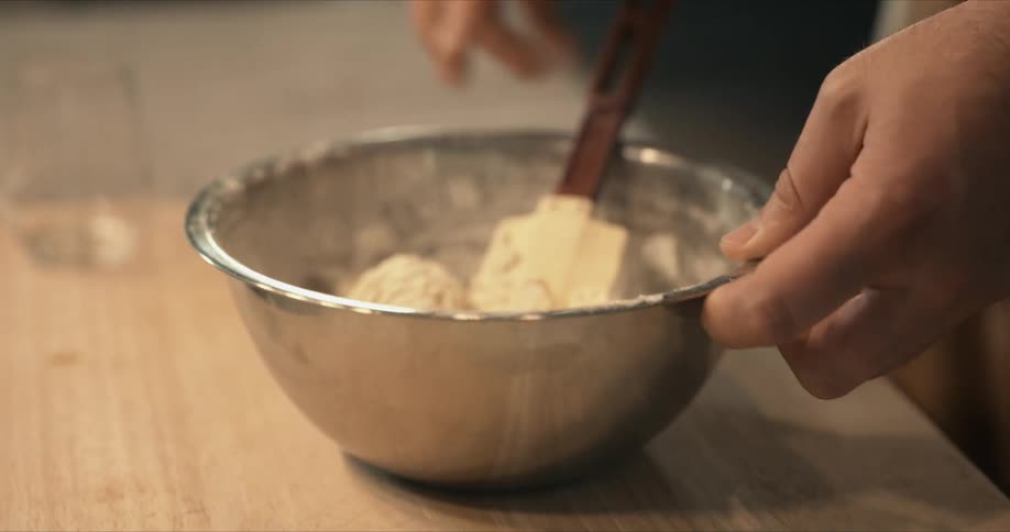 A person is mixing the dough in the bowl