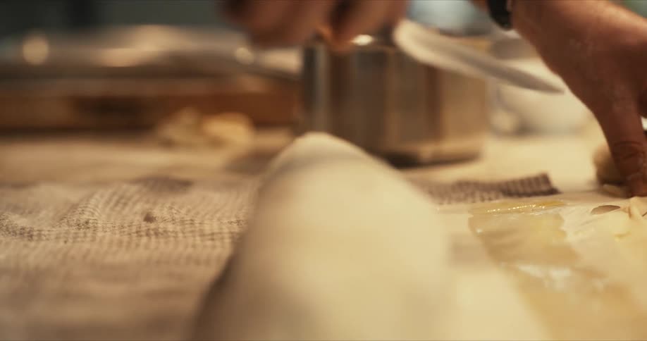 A chef uses a knife to carefully trim the excess dough before baking
