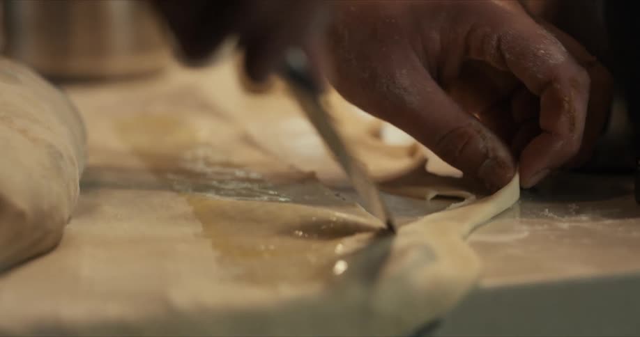 A person is cutting the dough with a knife