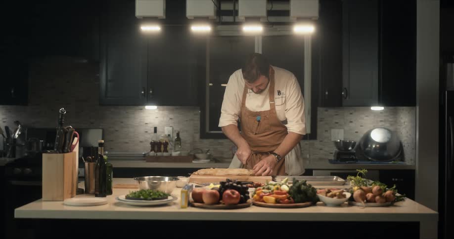 A man is cutting food in the kitchen