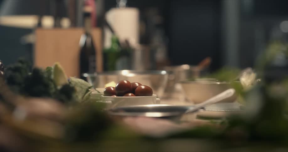 Olives sit among dishes and bowls on counter near a wine bottle