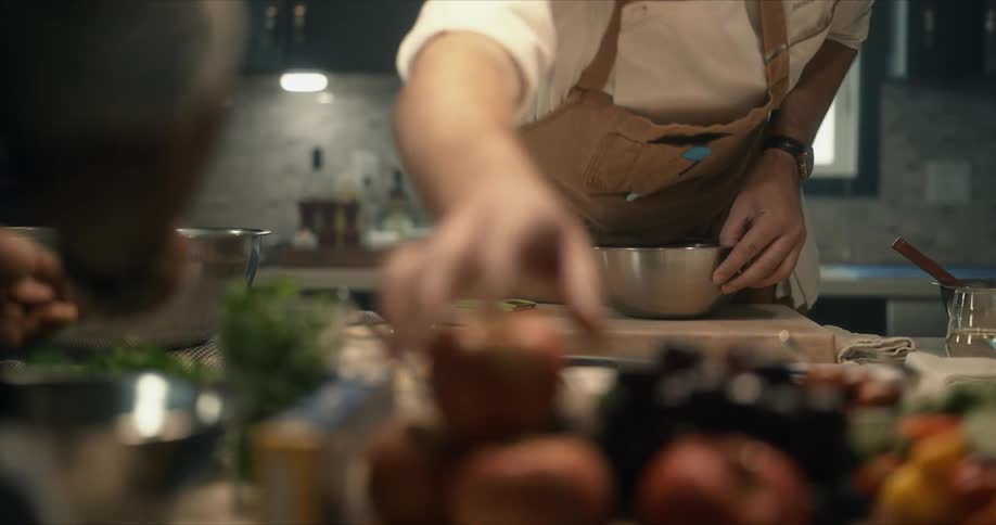 Chef picks up an apple to slice inside a bowl in the kitchen