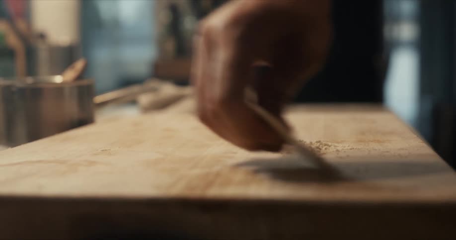 A person is removing the flour from the cutting board