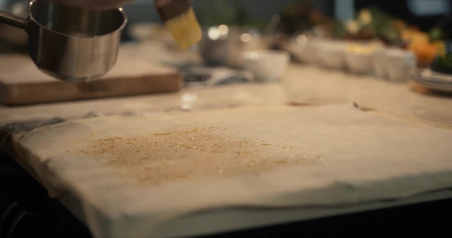 A person is dripping oil on the sheet of dough