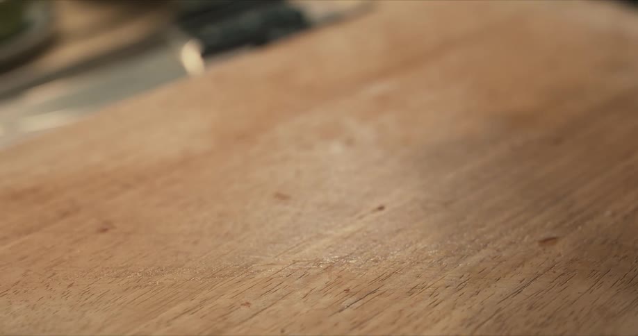 Man manipulates a piece of raw meat on wooden chopping board