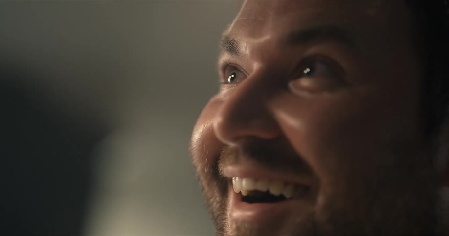 A man looks up smiling then laughing