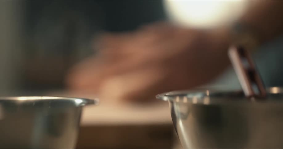 A person holds a piece of dough on a cutting board