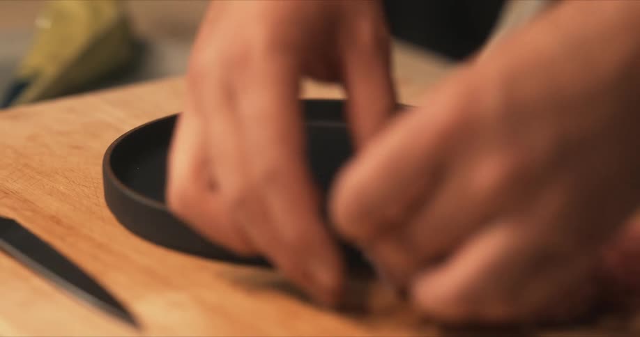 A man is placing sliced fish on a black plate